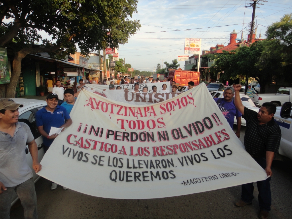 Spandoek met de tekst “Wij zijn allemaal Ayotzinapa”, “Niet vergeven, of vergeten”, “Bestraf de verantwoordelijken”, “Levend hebben ze hen meegenomen, levend willen we hen terug”